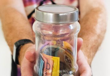 man holding a jar full of money
