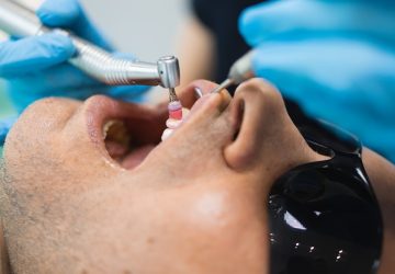 Dentist doing teeth cleaning procedure for male patient. Professional dental hygiene