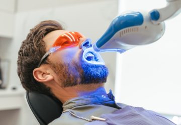 bearded man patient whitening teeth in modern dental clinic