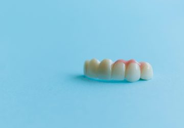 Artificial teeth on a blue background, dental crowns. Concept of dental crowns and bridges