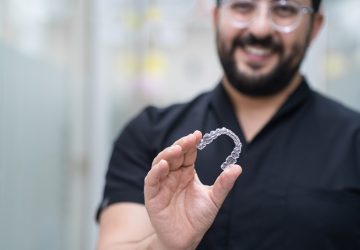Positive dentist demonstrating clear aligners used for teeth straightening in stomatology center
